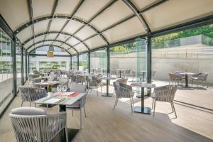 a restaurant with tables and chairs and glass walls at Barceló Costa Vasca in San Sebastián