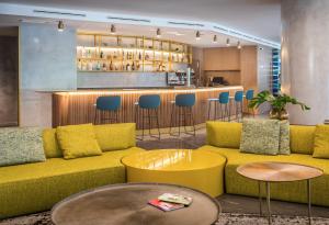 a living room with a yellow couch and a bar at Barceló Costa Vasca in San Sebastián