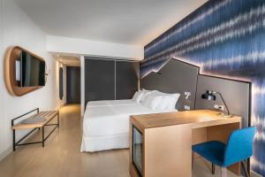 a hotel room with a bed and a desk and a tv at Barceló Costa Vasca in San Sebastián