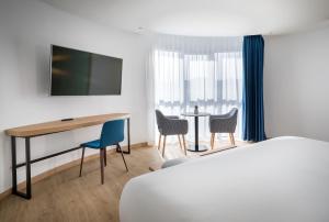 a hotel room with a bed and a desk and chairs at Barceló Costa Vasca in San Sebastián