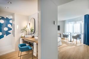 a bathroom with a sink and a vanity with a blue chair at Barceló Costa Vasca in San Sebastián