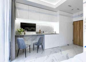 a kitchen with a counter and two chairs and a table at Apartament przy Targach Poznań in Poznań