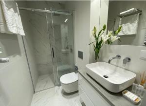 a white bathroom with a sink and a shower at Apartament przy Targach Poznań in Poznań