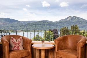 a balcony with two chairs and a table and mountains at Landhaus Leopoldhof in St. Wolfgang
