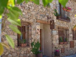 un edificio de piedra con ventanas y macetas. en Agroturismo El Mirador de la Cigüeña en Cabanillas del Monte