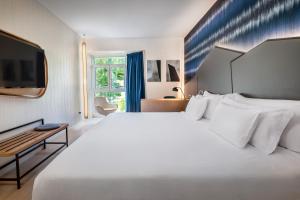 a bedroom with a large white bed and a television at Barceló Costa Vasca in San Sebastián