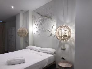 a hotel room with a white bed and a white wall at Hotel Galería Essentia in Aracena