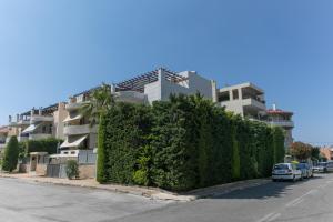 a building with a green hedge in front of a street at Riviera Pool Villa - Golf Athens in Athens