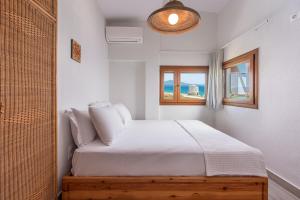 a white bedroom with a bed and a window at Windmill Villa in Kalives Poligirou