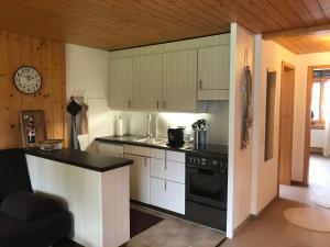 a kitchen with white cabinets and a black stove at Ferienwohnung Résidence Sonnegg - Hein in Zweisimmen