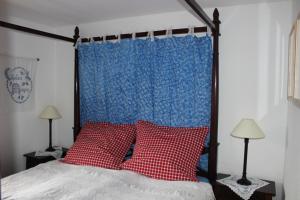 a bed with two red pillows and a blue curtain at Matti-Tinoll in Grimentz