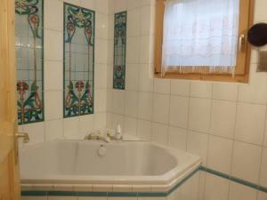 a white tub in a bathroom with stained glass windows at Matti-Tinoll in Grimentz