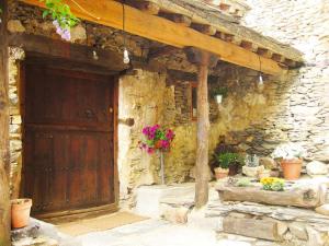 a stone building with a wooden door and flowers at Casa Rural Sobre Fábulas in Prádena de Atienza