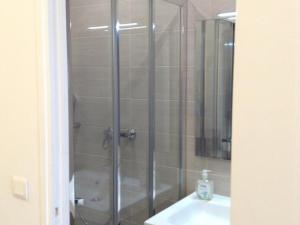 prysznic ze szklanymi drzwiami obok umywalki w obiekcie Hôtel Richard w Paryżu