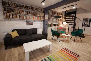 a living room with a black couch and green chairs at BED and BOOK hostel in Varna City