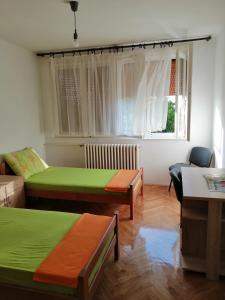 una camera con due letti, un divano e una finestra di Apartman KIKA a Sombor