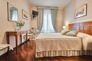 a bedroom with a bed and a desk and a window at Locanda De' Ciompi in Florence