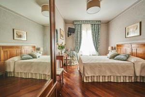 a hotel room with two beds and a mirror at Locanda De' Ciompi in Florence