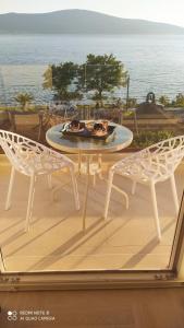 duas cadeiras e uma mesa numa varanda com o oceano em Villa Providenca apartments em Tivat