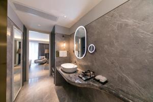 a bathroom with a sink and a mirror on a wall at Mercure Turpan Downtown in Turfan +77 photos