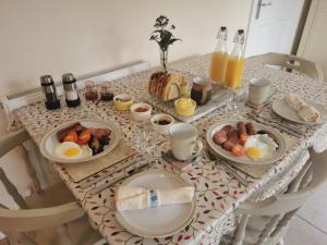 a table with plates of breakfast foods and bottles of orange juice at The Garden Room in Leiston