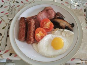 um prato de pequeno-almoço com ovos, salsicha e tomates em The Garden Room em Leiston