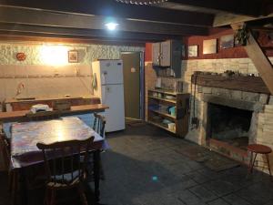 cocina con chimenea, mesa y nevera en Lambae, en Barra de Valizas