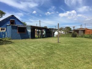 una casa azul en un campo con un patio en La Azurra, en Barra de Valizas