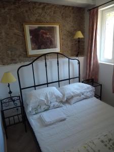 una camera da letto con letto, lenzuola e cuscini bianchi di La Petite Grange a Reynès