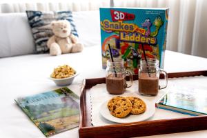 a tray with cookies and a box of snacks on a bed at Ramada Hotel & Suites by Wyndham Coventry in Coventry