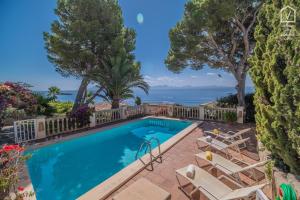 a swimming pool with chairs and trees and the ocean at TRES PINOS Alcanada in Alcudia