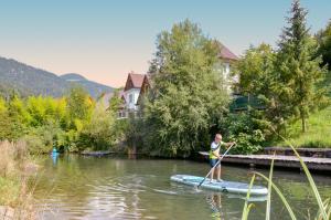 a woman on a paddle board in the water at Apartments Povh in Ljubno
