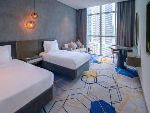 a hotel room with two beds and a couch at Pullman Sharjah in Sharjah