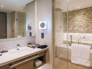 a bathroom with a sink and a shower at Pullman Sharjah in Sharjah