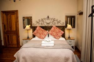 a bedroom with a large bed with two towels on it at Die Herehuis in Beaufort West
