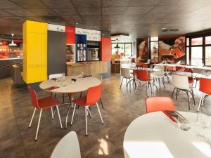 a dining room with tables and chairs in a restaurant at Ibis Évry-Courcouronnes in Evry-Courcouronnes