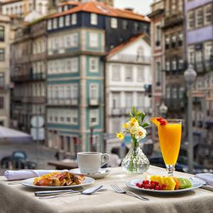 una mesa con platos de comida y un vaso de zumo de naranja en Porto A.S. 1829 Hotel en Oporto