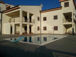 a villa with a swimming pool in front of a building at Lina Apartments C1 in Ginosa Marina