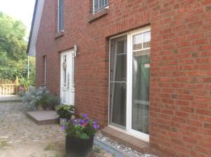 a brick house with a window and purple flowers at Auszeit am Haffufer in Wilhelmshof