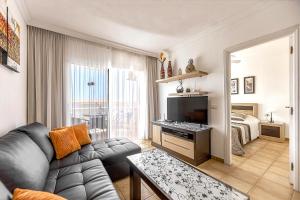 sala de estar con sofá, TV y cama en Apartamentos la Mar, en Puerto de Santiago
