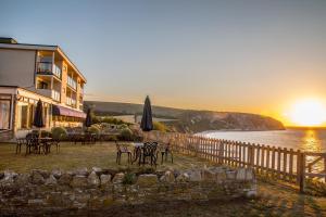 a building with chairs and an umbrella and the sunset at The Pines Hotel in Swanage