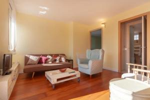 een woonkamer met een bank en een stoel bij Can Stella, luminoso apartamento de playa en Costa Dorada - Tarragona in Tarragona