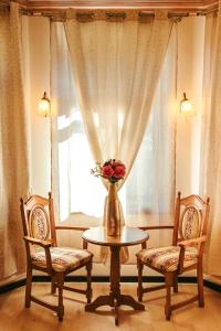 a vase with flowers on a table in front of a window at Vila Genia in Câmpulung Moldovenesc