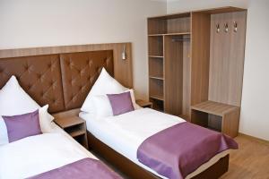 1 dormitorio con 2 camas con almohadas moradas en Ata Hotel - Self Check-in en Hamburgo