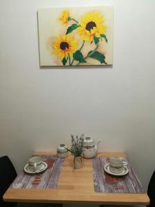 a table with two plates and a painting of sunflowers at Appartamento Oxygen in Riva del Garda