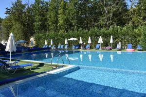 a large swimming pool with chairs and umbrellas at Apartment FREEDOM in Shkorpilovtsi
