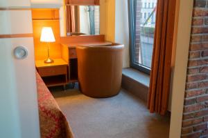 Cette chambre comprend un lit, un bureau et une fenêtre. dans l'établissement Hotel Vaidila, à Alytus