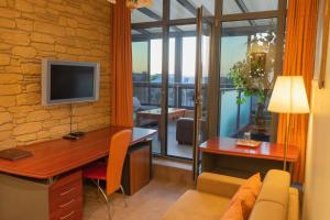 a living room with a desk and a television in a room at Hotel Vaidila in Alytus