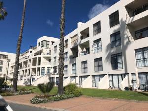 a white building with palm trees in front of it at Santos 27 Mossel Bay in Mossel Bay