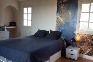 a bedroom with a blue bed and two windows at Villa Font Garenne in Crillon-le-Brave